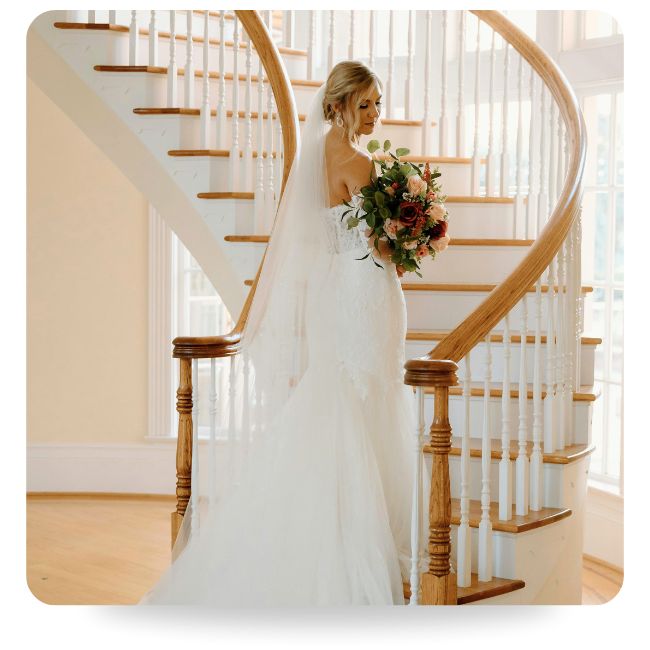 Bride standing on end of staircase looking over shoulder.